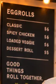 The Rollini chalkboard menu listing Classic, Spicy Chicken, Loaded Veggie and Dessert Roll